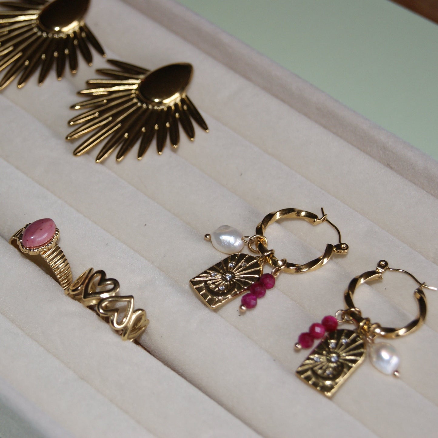 Gouden sieraden met roze bedeltjes